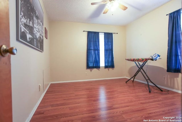 spare room with ceiling fan, wood-type flooring, and a textured ceiling