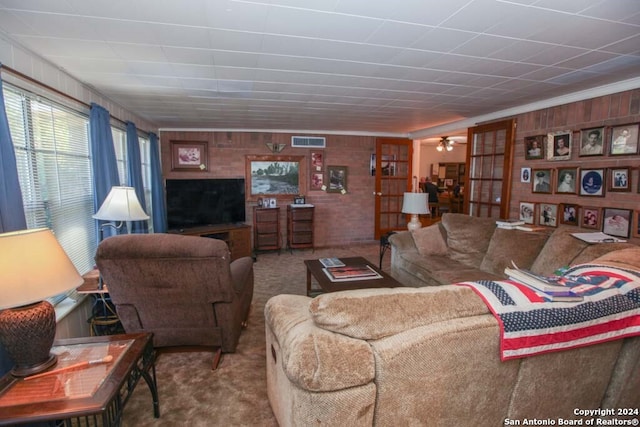 carpeted living room with wood walls and ornamental molding