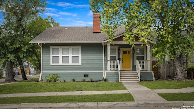 bungalow-style home featuring a front yard, crawl space, roof with shingles, and a chimney