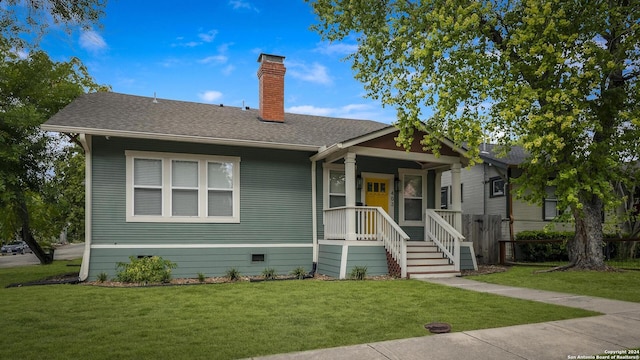 bungalow-style house with covered porch, roof with shingles, crawl space, a chimney, and a front yard