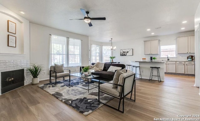 living room with light hardwood / wood-style flooring, a brick fireplace, and plenty of natural light