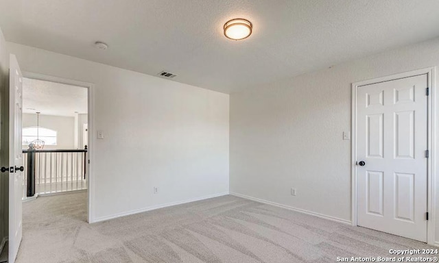 unfurnished room with light colored carpet and a textured ceiling