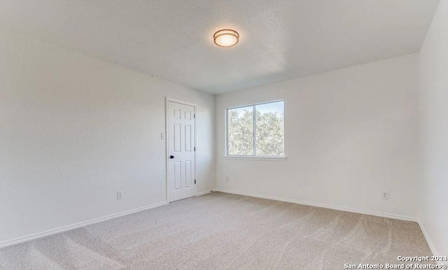 carpeted spare room featuring a textured ceiling