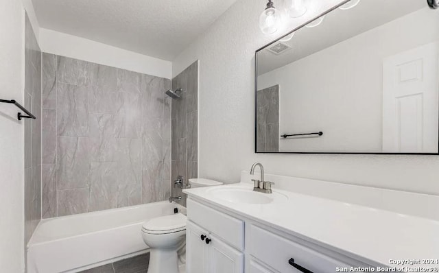 full bathroom with tile patterned floors, a textured ceiling, toilet, vanity, and tiled shower / bath