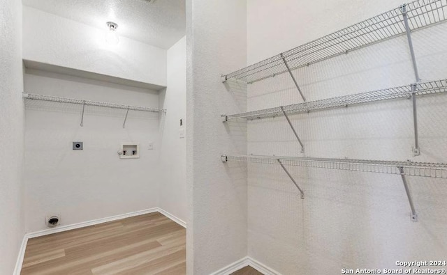 laundry room featuring hookup for an electric dryer, hookup for a washing machine, a textured ceiling, and hardwood / wood-style floors