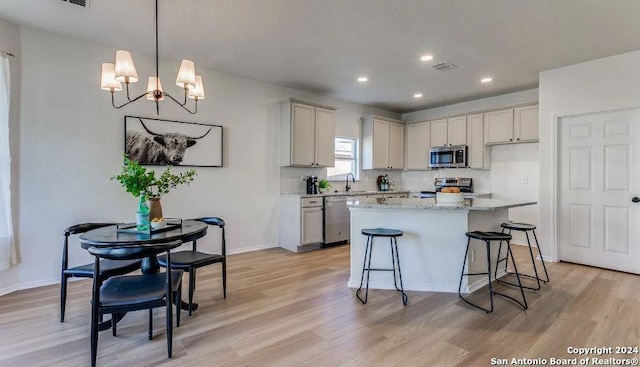 kitchen featuring light stone countertops, appliances with stainless steel finishes, pendant lighting, an inviting chandelier, and a center island