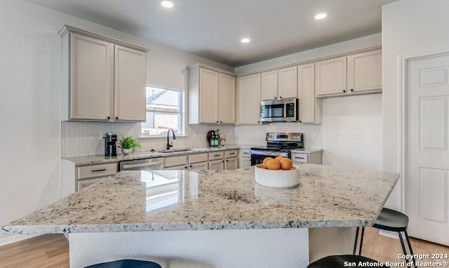 kitchen featuring light stone countertops, appliances with stainless steel finishes, a kitchen island, and a breakfast bar area