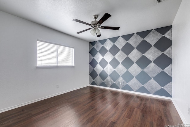 empty room featuring a textured ceiling, dark hardwood / wood-style floors, and ceiling fan