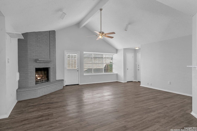 unfurnished living room featuring ceiling fan, dark hardwood / wood-style floors, vaulted ceiling with beams, a textured ceiling, and a fireplace