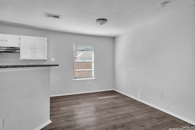 unfurnished dining area with dark hardwood / wood-style floors and a textured ceiling