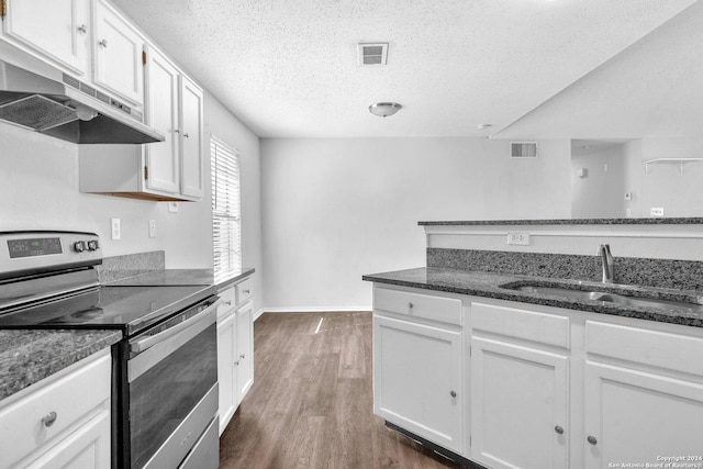 kitchen featuring stainless steel range with electric stovetop, dark stone countertops, white cabinets, and sink