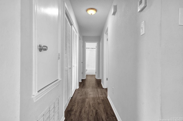 hall with dark hardwood / wood-style flooring and a textured ceiling