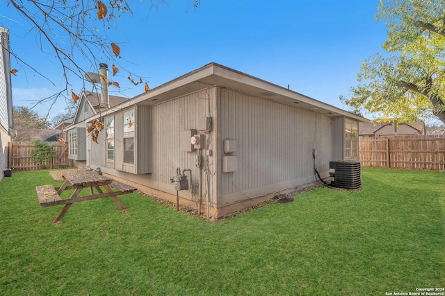 rear view of property with cooling unit and a yard