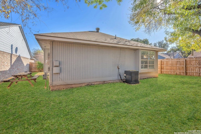 back of property featuring a lawn and central AC