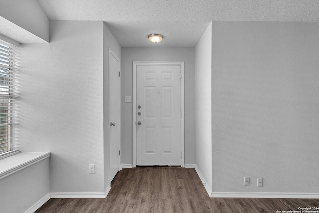 hallway featuring a textured ceiling, hardwood / wood-style flooring, and a healthy amount of sunlight