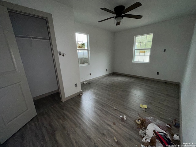 unfurnished bedroom featuring a closet, multiple windows, ceiling fan, and dark hardwood / wood-style flooring