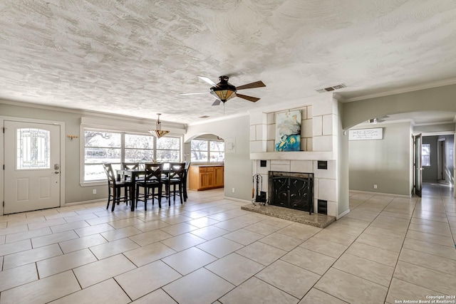 tiled living room featuring ceiling fan, a textured ceiling, and ornamental molding