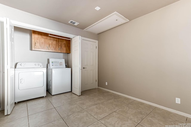 washroom with cabinets, light tile patterned floors, and washing machine and clothes dryer