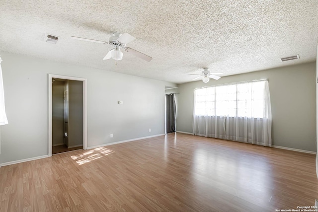 empty room with a textured ceiling, light hardwood / wood-style floors, and ceiling fan