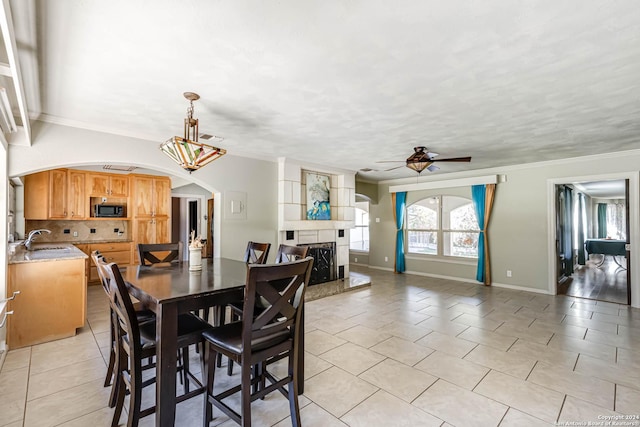 dining space with ceiling fan, light tile patterned flooring, crown molding, and sink