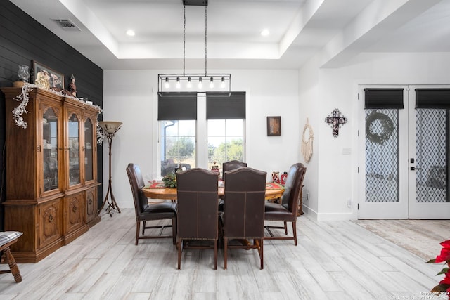 dining room with a raised ceiling, light hardwood / wood-style flooring, and french doors