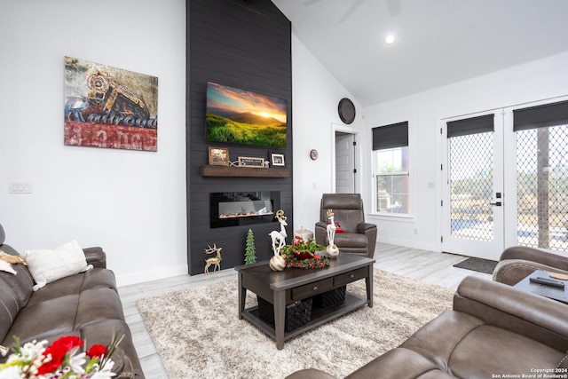 living room with a large fireplace, light hardwood / wood-style floors, high vaulted ceiling, and ceiling fan