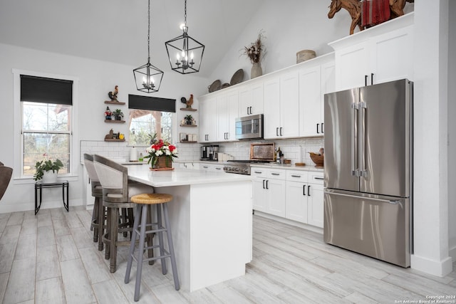 kitchen with white cabinetry, a kitchen island, stainless steel appliances, and lofted ceiling