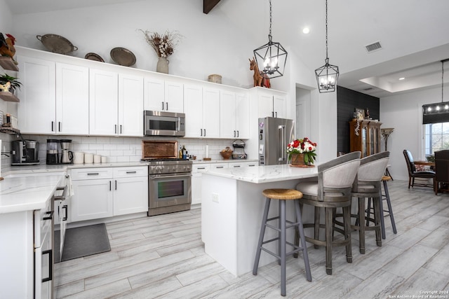 kitchen with tasteful backsplash, high quality appliances, a center island, and white cabinets