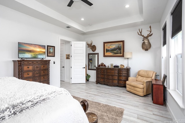 bedroom featuring a tray ceiling, ceiling fan, and light hardwood / wood-style flooring