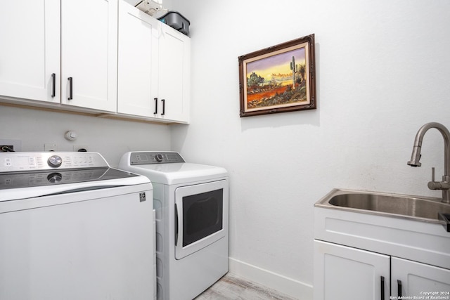 washroom with cabinets, separate washer and dryer, light hardwood / wood-style floors, and sink