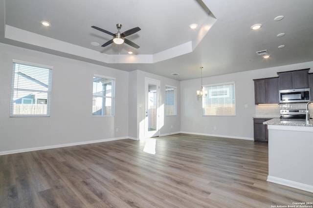 unfurnished living room featuring dark hardwood / wood-style flooring, a raised ceiling, and plenty of natural light