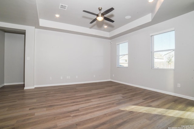 empty room featuring ceiling fan, dark hardwood / wood-style flooring, and a tray ceiling