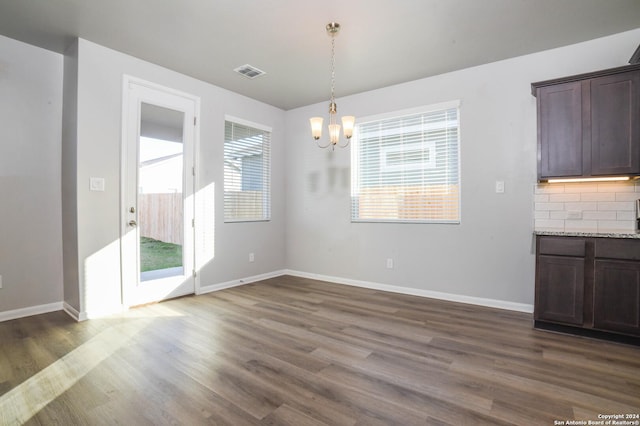 unfurnished dining area featuring dark wood-type flooring and an inviting chandelier