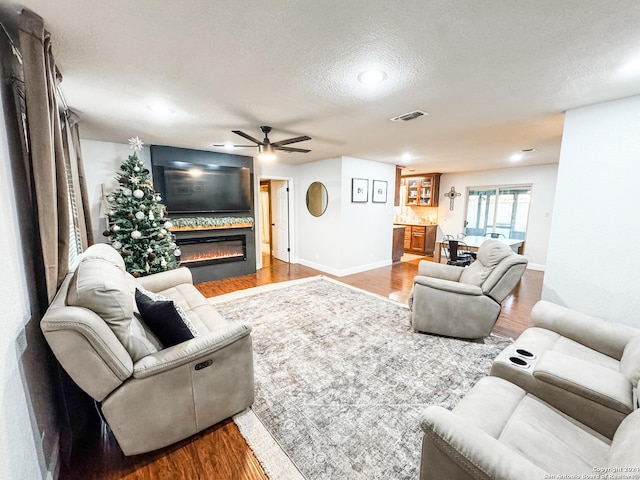 living room featuring ceiling fan, light hardwood / wood-style floors, and a textured ceiling