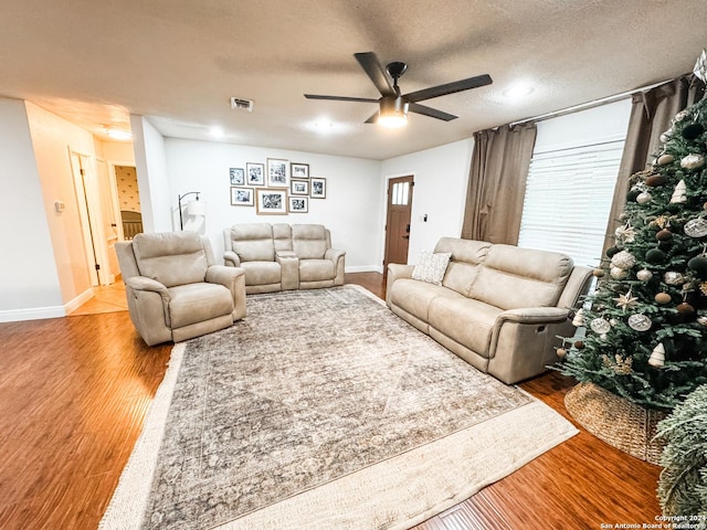 living room with hardwood / wood-style floors, ceiling fan, and a textured ceiling