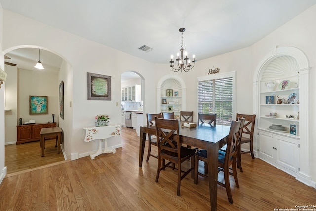 dining room with built in shelves, a notable chandelier, and hardwood / wood-style flooring