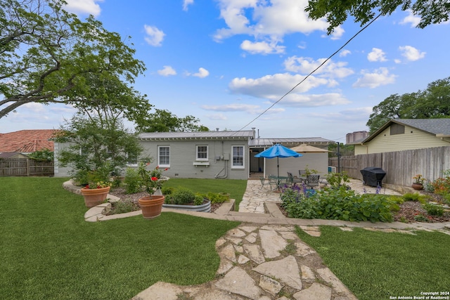 rear view of property featuring a lawn and a patio area