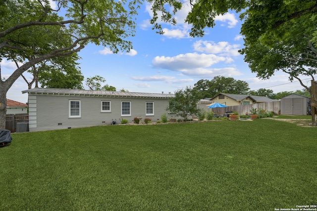 back of house with a lawn, central AC unit, and a storage unit