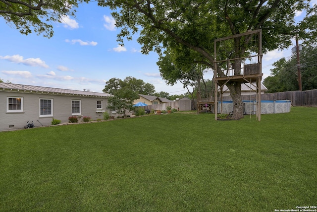 view of yard featuring a fenced in pool and a shed