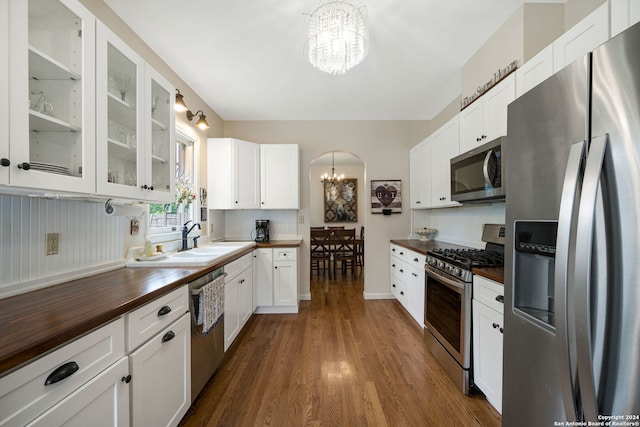 kitchen with butcher block countertops, white cabinetry, appliances with stainless steel finishes, and an inviting chandelier