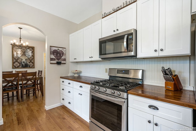 kitchen with wooden counters, stainless steel appliances, a chandelier, light hardwood / wood-style floors, and white cabinetry