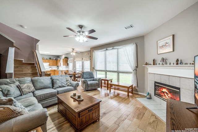 living room with ceiling fan, a fireplace, and light hardwood / wood-style floors