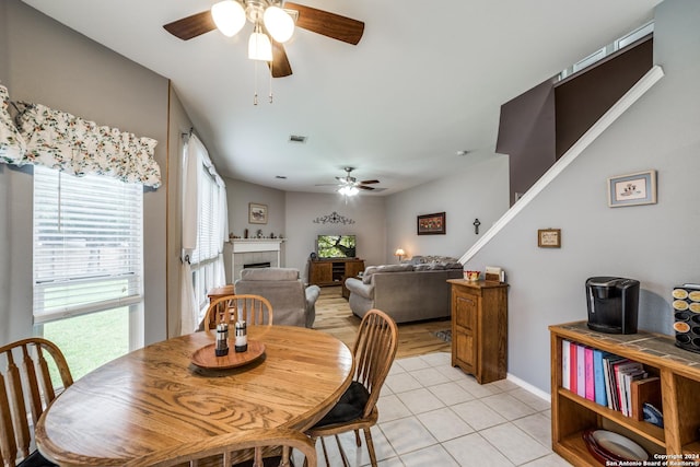 dining space featuring a fireplace, ceiling fan, a healthy amount of sunlight, and light tile patterned flooring