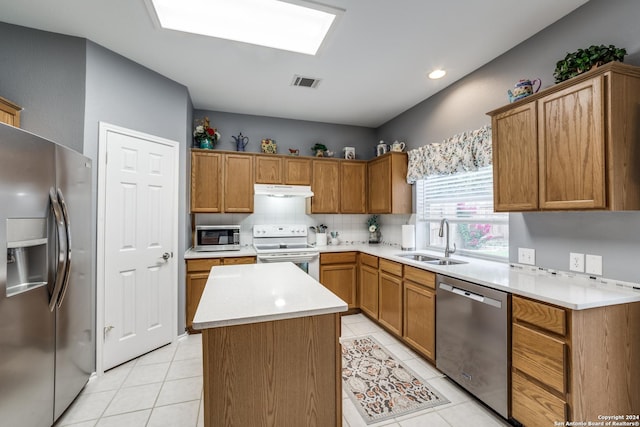 kitchen with sink, a kitchen island, light tile patterned flooring, and appliances with stainless steel finishes