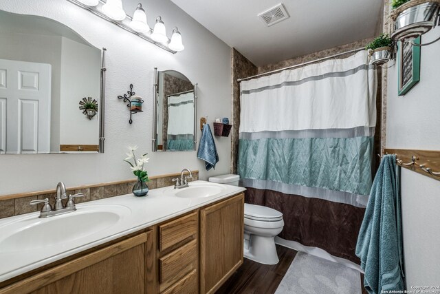 bathroom with a shower with shower curtain, hardwood / wood-style floors, vanity, and toilet