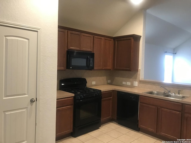 kitchen featuring lofted ceiling, backsplash, black appliances, sink, and light tile patterned floors