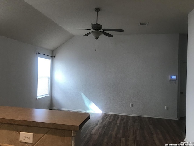 spare room featuring ceiling fan, dark wood-type flooring, and lofted ceiling