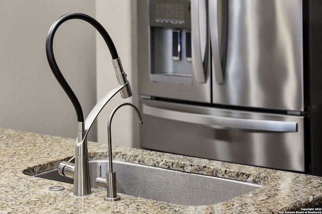 room details featuring stainless steel fridge and light stone countertops