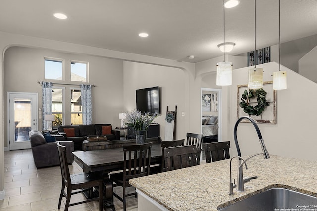 kitchen with light tile patterned floors, decorative light fixtures, light stone counters, and sink