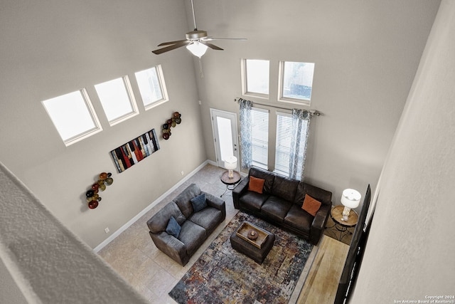 living room with ceiling fan, a towering ceiling, and light tile patterned floors